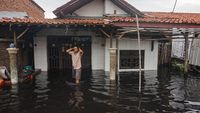 Warga berjalan melewati depan rumahnya yang tergenang banjir di Pabean, Kota Pekalongan, Jawa Tengah, Rabu (7/1/2026). Banjir setinggi sekitar 50-80 centimeter itu menggenangi perkampungan daerah Pabean yang menyebabkan aktifitas perekonomian dan pendidikan terganggu dengan sebanyak 300 KK terdampak banjir akibat tanggul Sungai Bremi jebol. ANTARA FOTO/Harviyan Perdana Putra